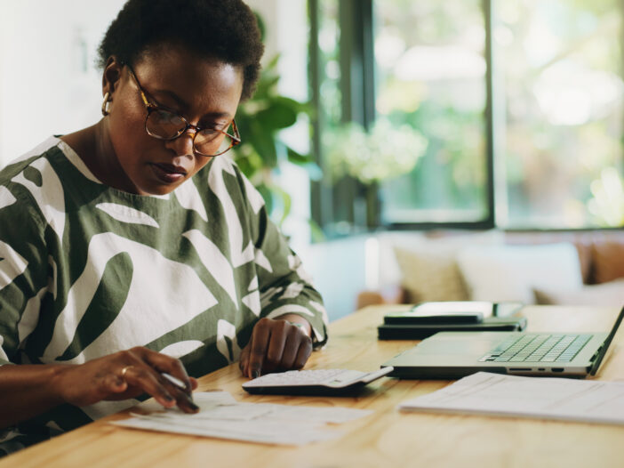 Finance, budgeting and black woman with invoice in home for financial planning, savings or auditing. Wealth, person or laptop with receipt documents for tax return, account review or asset management